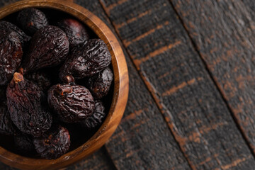 A Bowl of Dark Dried Mission Figs on a Wood Table