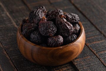 A Bowl of Dark Dried Mission Figs on a Wood Table