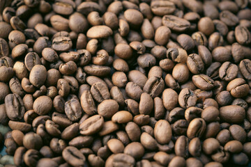 A pile of natural brown roasted coffee beans.