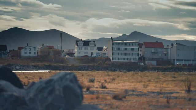 View of the town of Bleik on the Andoya island, Norway. Houses stand along the shore. Heavy clouds cover the sky. Slow-motion, pan left.