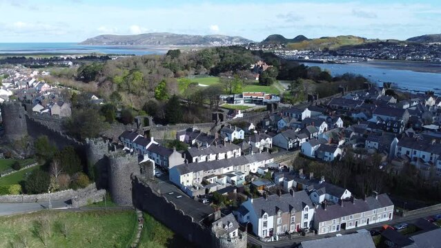 Welsh holiday cottages enclosed in Conwy castle battlements stone walls aerial view orbiting coast