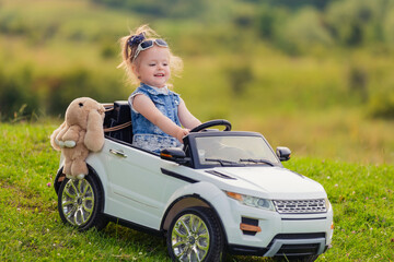 child rides in his car in nature