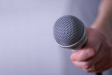 A man holds a microphone in his hand with room to copy.