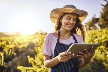 Farming in the age of the app. Shot of a young woman using a digital tablet on a farm.