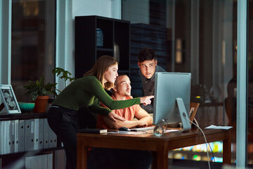 The internet is there to make things easier. Shot of a group of designers looking at something on a computer while working late.