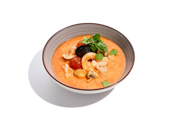 Traditional asian soup - tom yam with prawn and coconut milk isolated on white background. Tom yam kung with seafood and coriander in gray bowl on white background.