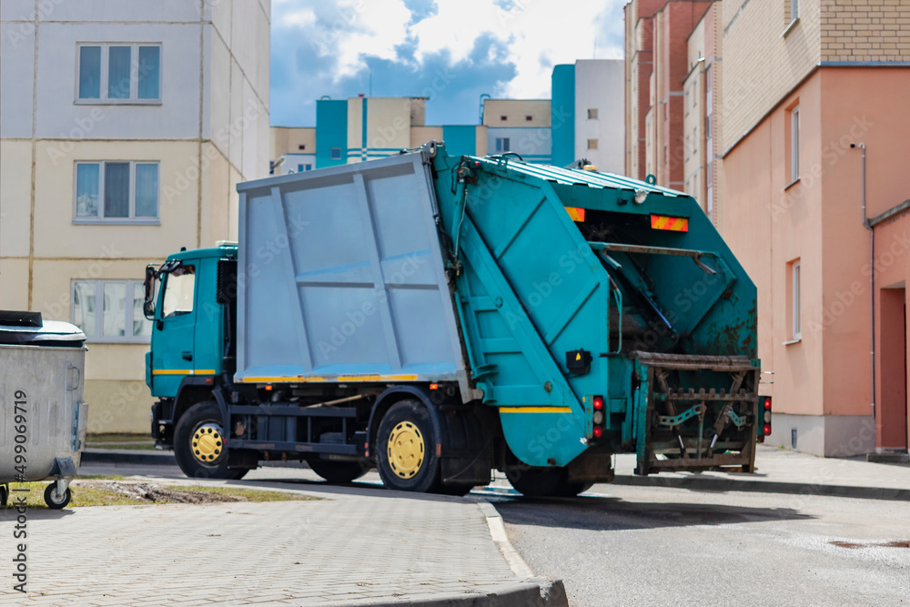 Poster an automobile garbage truck collects garbage in residential areas of a modern city. close-up of a ca