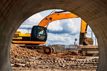 Heavy excavator at the construction site. View of the excavator through the iron pipe. Construction...