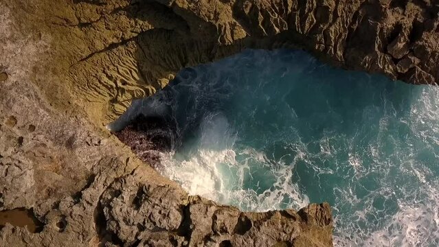 Daring aerial view flight slowly 360 circle drone shotBig ocean waves crashing on the rocks of Devil's Tear at Lembongan. Rock cliff Beach at midday noon time Bali 2017. Cinematic
