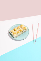 Cheese maki roll on blue ceramic plate. Sushi roll in Caesar style on coloured backdrop. Sushi menu concept. Modern japanesse food. Maki sushi with cheese in minimal style