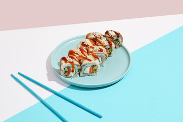 Canada Maki roll with eel on modern coloured background. Sushi roll with salmon, cheese, cucumber inside, eel and unagi sauce outside. Unagi maki sushi in minimal style. Japanese menu concept.