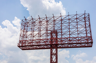 A view of an old sign, a red steel structure towering in anticipation of an advertisement.