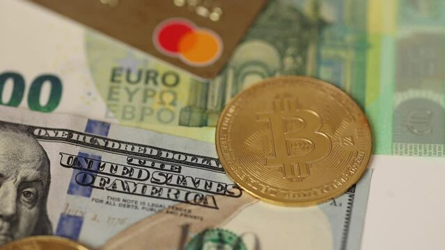 Golden bitcoins place on credit cards under US dollar and euro banknotes. Cryptocurrency concept. Close up