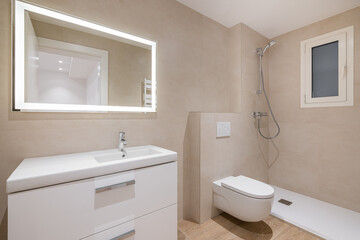Modern bathroom with beige tiles, shower, toilet and rectangular large mirror with lighting