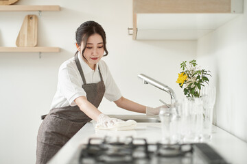 キッチンの拭き掃除をするアジア人女性 - obrazy, fototapety, plakaty