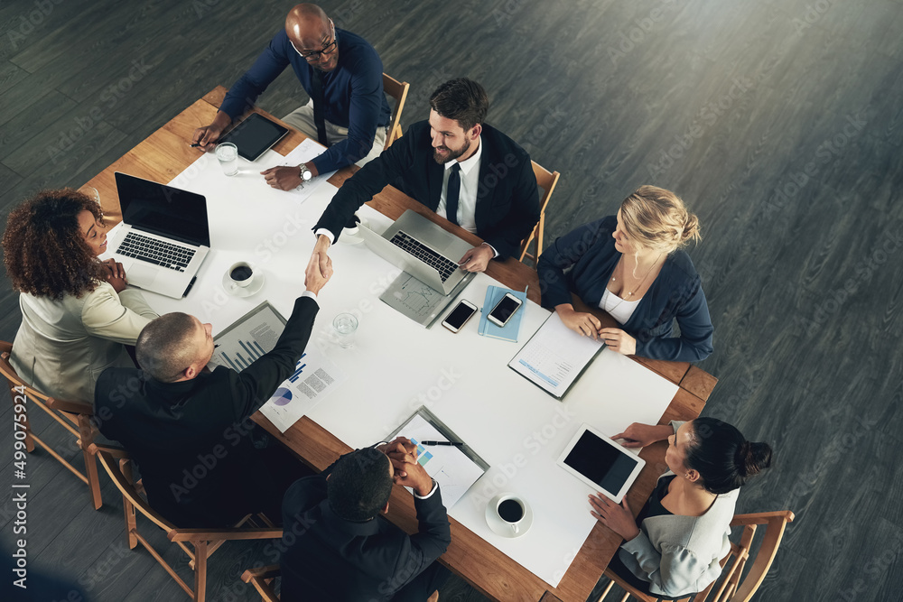 Poster Teaming up for more productivity. High angle shot of a team of businesspeople working around a table in the office.