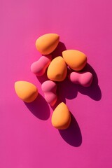makeup sponges on a pink background with hard shadows from the sun. High quality photo