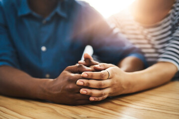 Put love first. Cropped shot of an unidentifiable man and woman holding hands on a table.