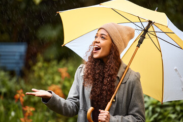 Making the best of a cold winters day. Shot of a young woman standing in the rain with an umbrella. © Alexis Scholtz/peopleimages.com