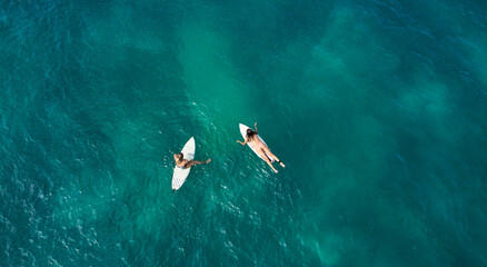 Aerial view of the ocean and surfer girls.