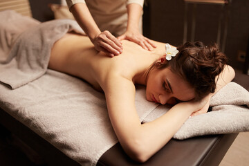 The masseuse gives a body massage to a young woman. Spa relaxation concept.