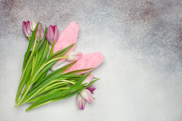 Easter concept. Tulips in the bag and bunny ears on a gray background. Top view. Copy space