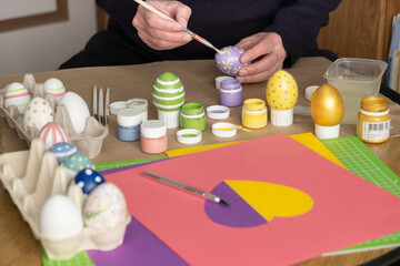 Man paints the Easter eggs, while enjoying DIY decorating at home. Man decorating colorful eggs. Hands painting easter eggs, preparation for holiday, easter celebration