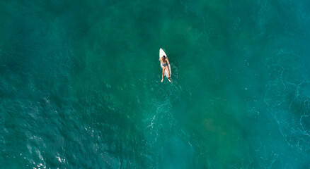 Aerial view of the ocean and surfer girl.