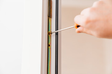 hands with a screwdriver repair, adjust or install metal-plastic windows