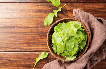 Fresh arugula leaves in brown bowl top view