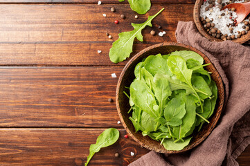 Fresh arugula leaves in brown bowl top view