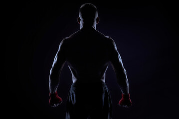 Kickboxer in red bandages posing on a blue background. Back view. The concept of mixed martial arts.