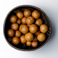 Macadamia nuts in cacaco cups top view on white background
