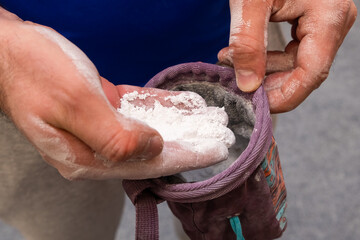 Climber applying chalk powder for rock climbing in bouldering gym. 