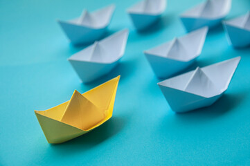 Leadership Concept - Yellow color paper ship origami leading the rest of the white paper ship on...