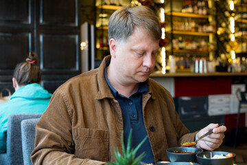 An adult male blond 40-45 years old having lunch in a cafe in a shopping center.