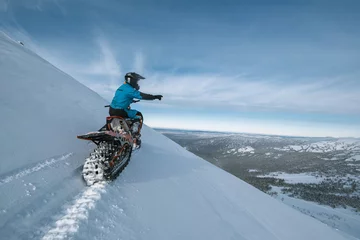 Fotobehang Snowbike rider on steep snowy slope. Modify motorcycle with ski and special snowmobile-style track instead of wheels © Annatamila