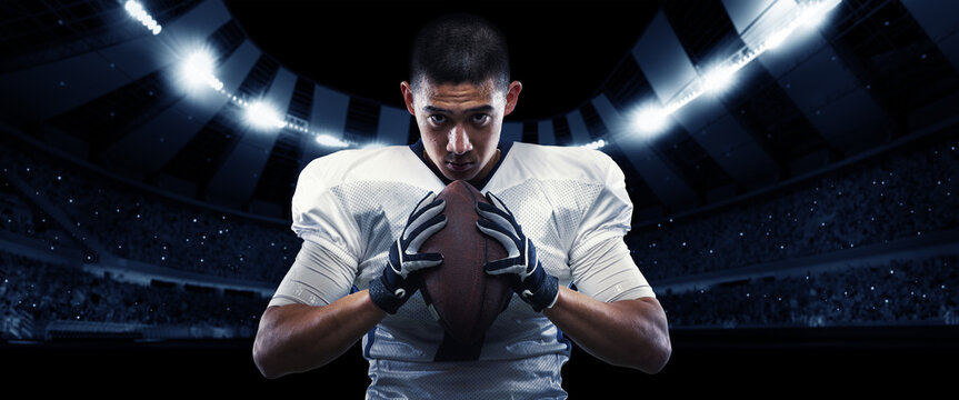 Closeup american football player in sports equipment grips the ball tightly against night stadium with spotlights background. Sport, championship, bowl concept
