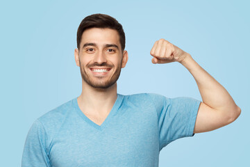 Young strong sporty athletic man in casual blue t-shirt, showing biceps after training in gym - Powered by Adobe