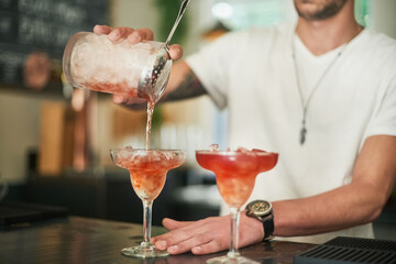 Whos thirsty. Cropped shot of an unidentifiable bartender pouring a cocktail behind the bar.
