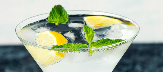 banner with serving mojito in a martini glass. drink with lemon, mint, soda and ice on a black and...