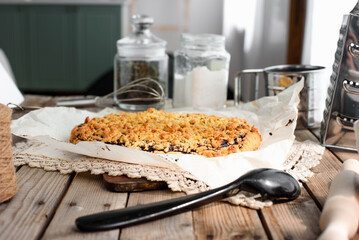 Grated pie with a golden crust in focus on the background of the kitchen. light from the side