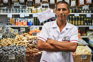 Hes been doing this his whole life. Portrait of a confident middle aged man standing with his arms folded at his market stall outside during the day.