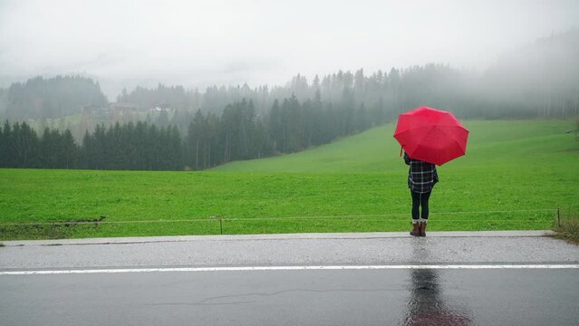 Portrait carefree attractive beautiful woman female happy asian girl with long dark curly hair holding transparent umbrella standing in alpine meadow in rainy weather rain smiling toothy looking at
