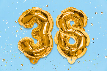 The number of the balloon made of golden foil, the number thirty-eight on a blue background with sequins. Birthday greeting card with inscription 38. Numerical digit, Celebration event, template.