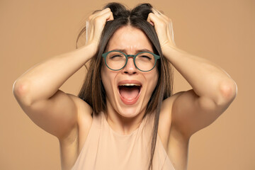 Closeup portrait stressed frustrated woman with glasses screaming isolated on beige background....