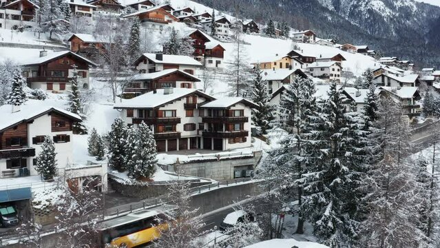 flying towards a snowy mountain village with a yellow bus passing by