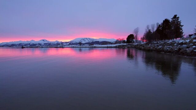Breathtaking sunset of a colorful sky in Scandinavia, sunset reflecting on the water revealing snow covered mountains