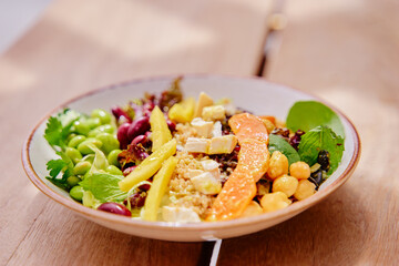 Salad with pumpkin, mango, beans,  lettuce and tofu on a wooden table. Healthy vegetarian food.