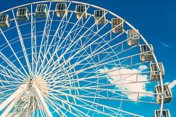 Ferris Wheel against blue cloudy sky on sunny weather